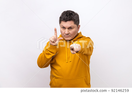 You are loser. Portrait of serious bossy man pointing at camera and showing lame or loser gesture, mocking your failures, wearing urban style hoodie. Indoor studio shot isolated on white background. 92146259
