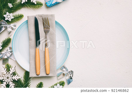 Christmas table place setting with christmas decor and plates, kine, fork and spoon. Christmas holiday background. Top view with copy space Christmas table place setting with christmas decor and plates, kine, fork and spoon. Christmas holiday background. Top view with copy space 92146862