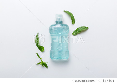 Mouthwash and fresh mint on colored background, top view with copy space for text Mouthwash and fresh mint on colored background, top view with copy space for text 92147104