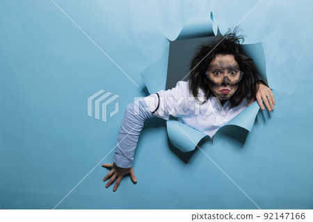 Crazy laughable scientist with amusing expression, dirty face and messy hair acting funny after failed toxic experiment. Lunatic bichemist with wacky hairstyle acting stupid after chemical explosion. 92147166