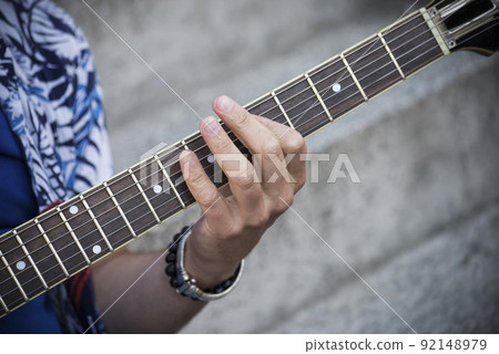Closeup of hand of man playing electric guitar in outdoor Closeup of hand of man playing electric guitar in outdoor 92148979