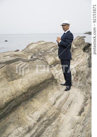 Middle-aged man in a suit staring at the sea Middle-aged man in a suit staring at the sea 92153871