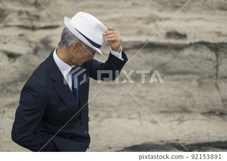 Middle-aged man in a suit staring at the sea Middle-aged man in a suit staring at the sea 92153891