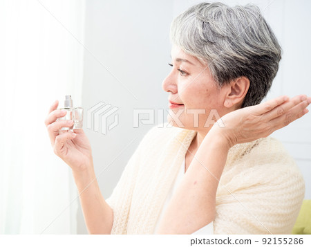 Portrait of mature aged asian woman 60s sprays perfume. Portrait of mature aged asian woman 60s sprays perfume. 92155286