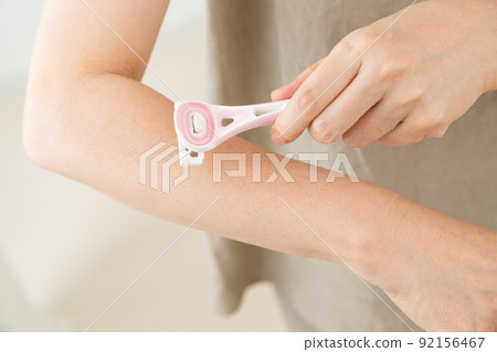 Middle woman shaving her arm Middle woman shaving her arm 92156467