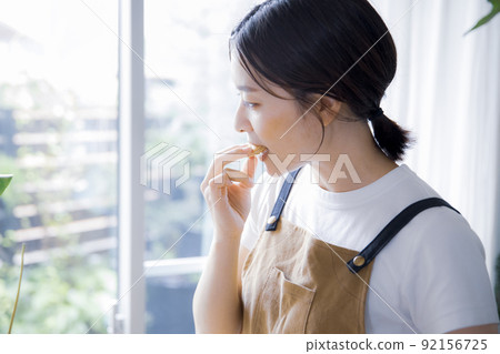 A woman in an apron eating sweets A woman in an apron eating sweets 92156725