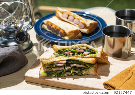 A classic camping meal that makes and eats hot sandwiches at an outdoor camp 92157447