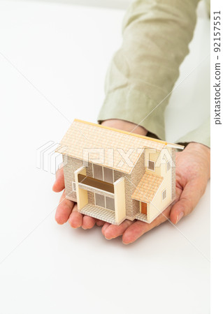Hand of a middle woman holding a house model of a house Hand of a middle woman holding a house model of a house 92157551