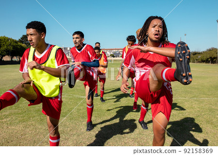 Multiracial male athletes stretching legs while standing on playground against clear sky, copy space 92158369