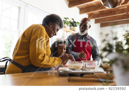 Image of happy african american grandparents and granddaughter baking in kitchen 92159392