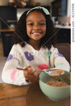 Vertical image of happy african american girl eating breakfast Vertical image of happy african american girl eating breakfast 92159496