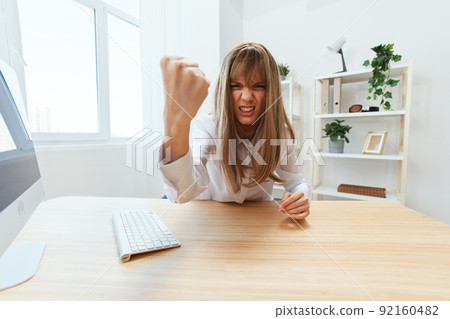 Angry evil blonde businesswoman screaming to subordinates shaking fist at camera sitting at workplace in modern office. Irritated director work on computer online in financial corporation. Wide angle Angry evil blonde businesswoman screaming to subordinates shaking fist at camera sitting at workplace in modern office. Irritated director work on computer online in financial corporation. Wide angle 92160482