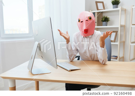 Pensive crazy businesswoman worker freelancer in pink fish mask work on computer online pondering or making decision thinking of problem solution spread hands in light modern office. Copy space Pensive crazy businesswoman worker freelancer in pink fish mask work on computer online pondering or making decision thinking of problem solution spread hands in light modern office. Copy space 92160498