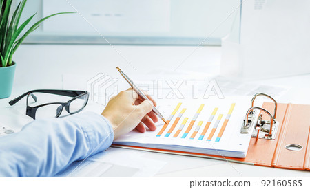 Finance. Female hand with calculator on financial graphs on desk Finance. Female hand with calculator on financial graphs on desk 92160585