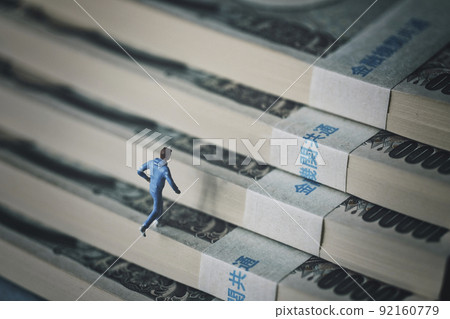 一個微型男人爬上一疊鈔票的樓梯 一個微型男人爬上一疊鈔票的樓梯 92160779