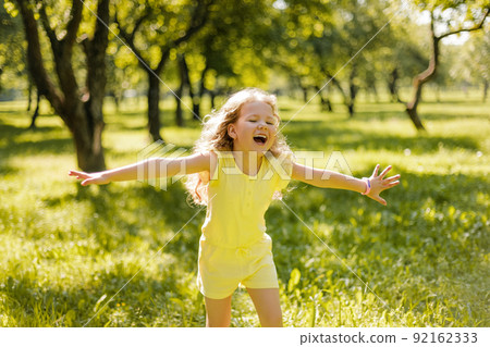 A happy child playing in a summer park. The girl is running, spinning, spinning and laughing. Entertainment during the summer holidays 92162333