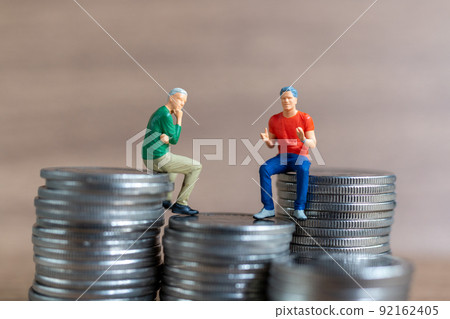 Miniature people A businessman is seated atop a mound of money 92162405