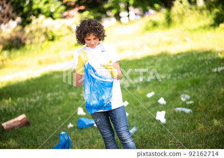 Curly-haired teen looking concentrated while gathering litter 92162714