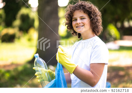 Curly-haired teen looking concentrated while gathering litter Curly-haired teen looking concentrated while gathering litter 92162718