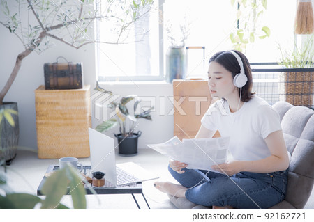 日本女性在明亮的房間裡使用耳機和筆記本電腦進行在線課程和遠程工作 92162721