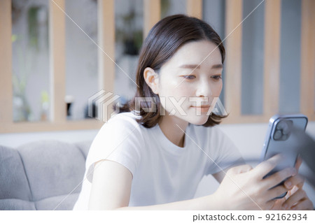 Japanese woman browsing the internet on her smartphone in a bright room 92162934