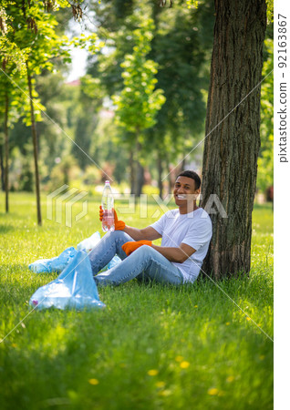 Guy sitting under tree smiling at camera 92163867