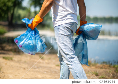 Man holding waste bags with back to camera Man holding waste bags with back to camera 92163914