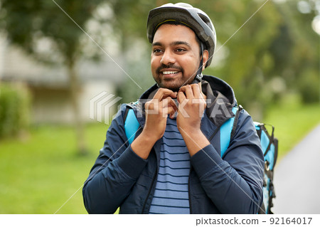 food delivery man fastening bicycle helmet in city food delivery man fastening bicycle helmet in city 92164017