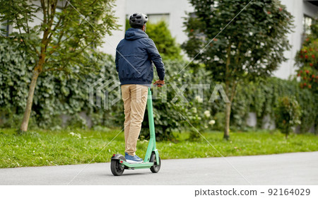 man in helmet riding electric scooter on street 92164029