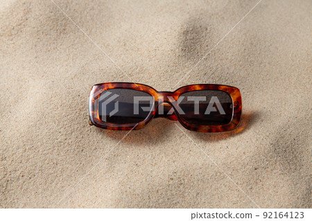 tortoiseshell sunglasses on beach sand 92164123