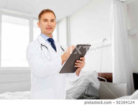 smiling male doctor with clipboard and stethoscope smiling male doctor with clipboard and stethoscope 92164124