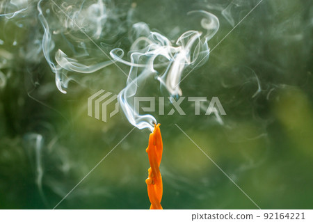 close up of smoking swirl candle in forest 92164221