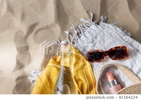 sunglasses, bag, water bottle, sunscreen on beach 92164224