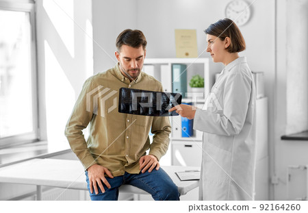 doctor showing x-ray to male patient at hospital 92164260