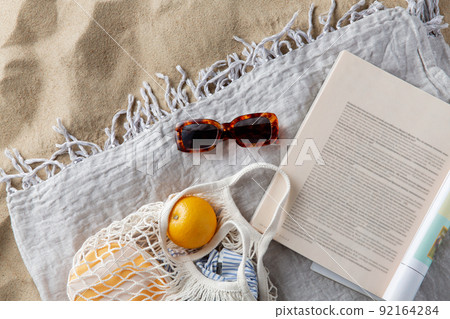 bag of oranges, sunglasses and magazine on beach bag of oranges, sunglasses and magazine on beach 92164284
