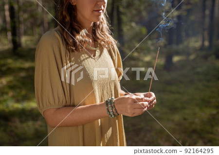 woman with smoking incense stick in forest 92164295