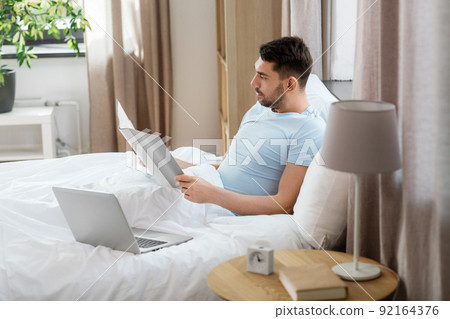 man with laptop working in bed at home bedroom man with laptop working in bed at home bedroom 92164376