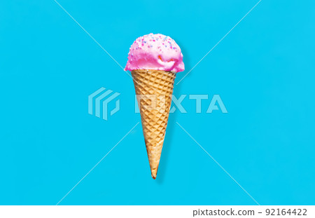 close up of pink ice cream in waffle cone on blue 92164422