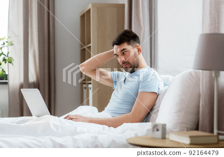 man with laptop in bed at home bedroom man with laptop in bed at home bedroom 92164479
