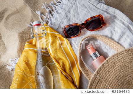 sunglasses, bag, water bottle, sunscreen on beach 92164485