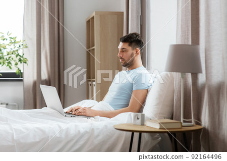 man with laptop in bed at home bedroom man with laptop in bed at home bedroom 92164496