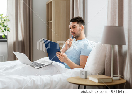 man with laptop working in bed at home bedroom 92164533