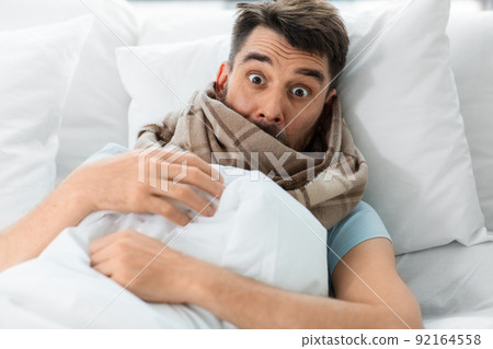 scared sick man in bed at home 92164558