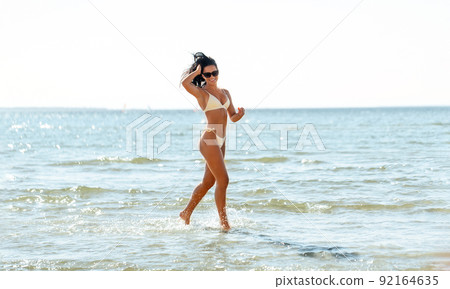 young woman in bikini swimsuit running on beach young woman in bikini swimsuit running on beach 92164635