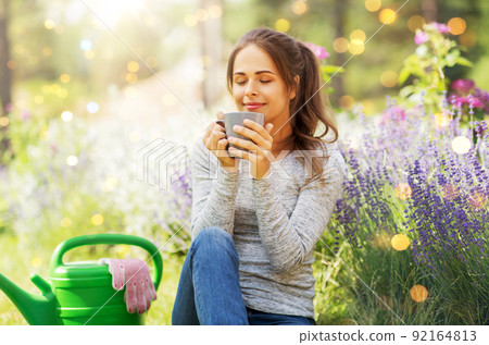 woman drinking tea or coffee at summer garden 92164813
