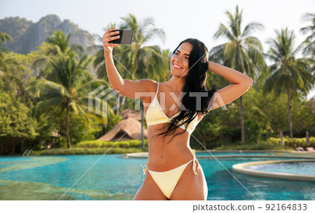 woman in bikini taking selfie over swimming pool woman in bikini taking selfie over swimming pool 92164833