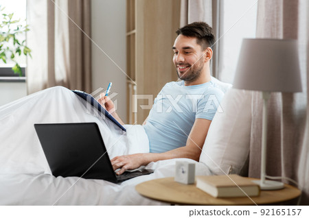 man with laptop working in bed at home bedroom man with laptop working in bed at home bedroom 92165157