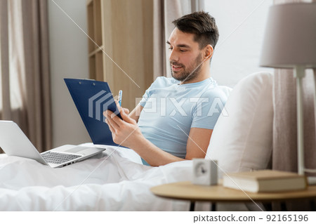 man with laptop working in bed at home bedroom man with laptop working in bed at home bedroom 92165196