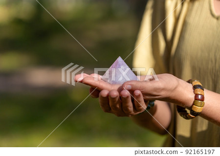 close up of hands holding crystal pyramid close up of hands holding crystal pyramid 92165197