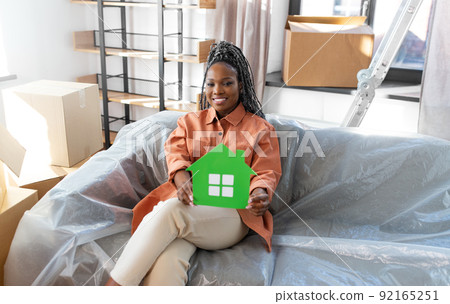 happy woman with green house and boxes moving home happy woman with green house and boxes moving home 92165251